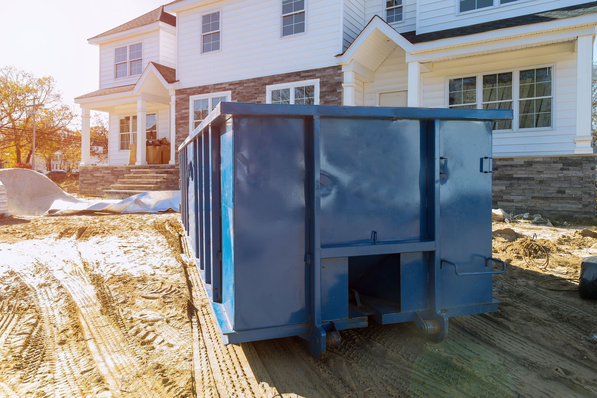 Blue dumpster in front of a house under construction.
