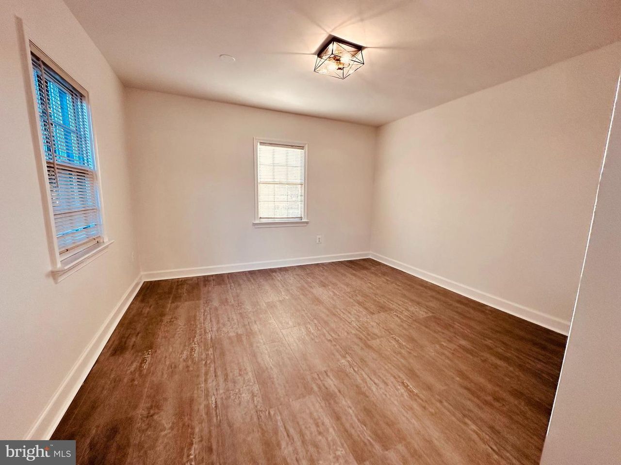 An empty room with hardwood floors and a window.