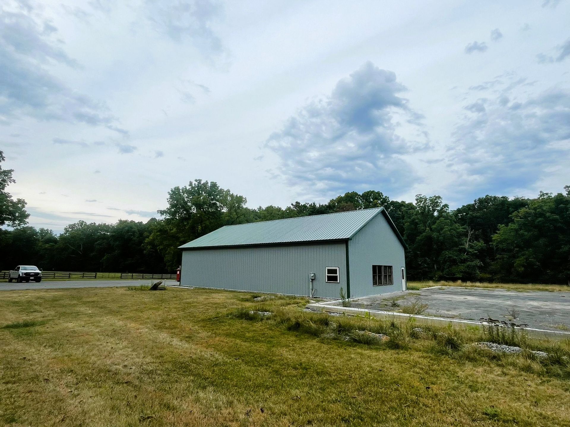 A large white barn is sitting in the middle of a grassy field.