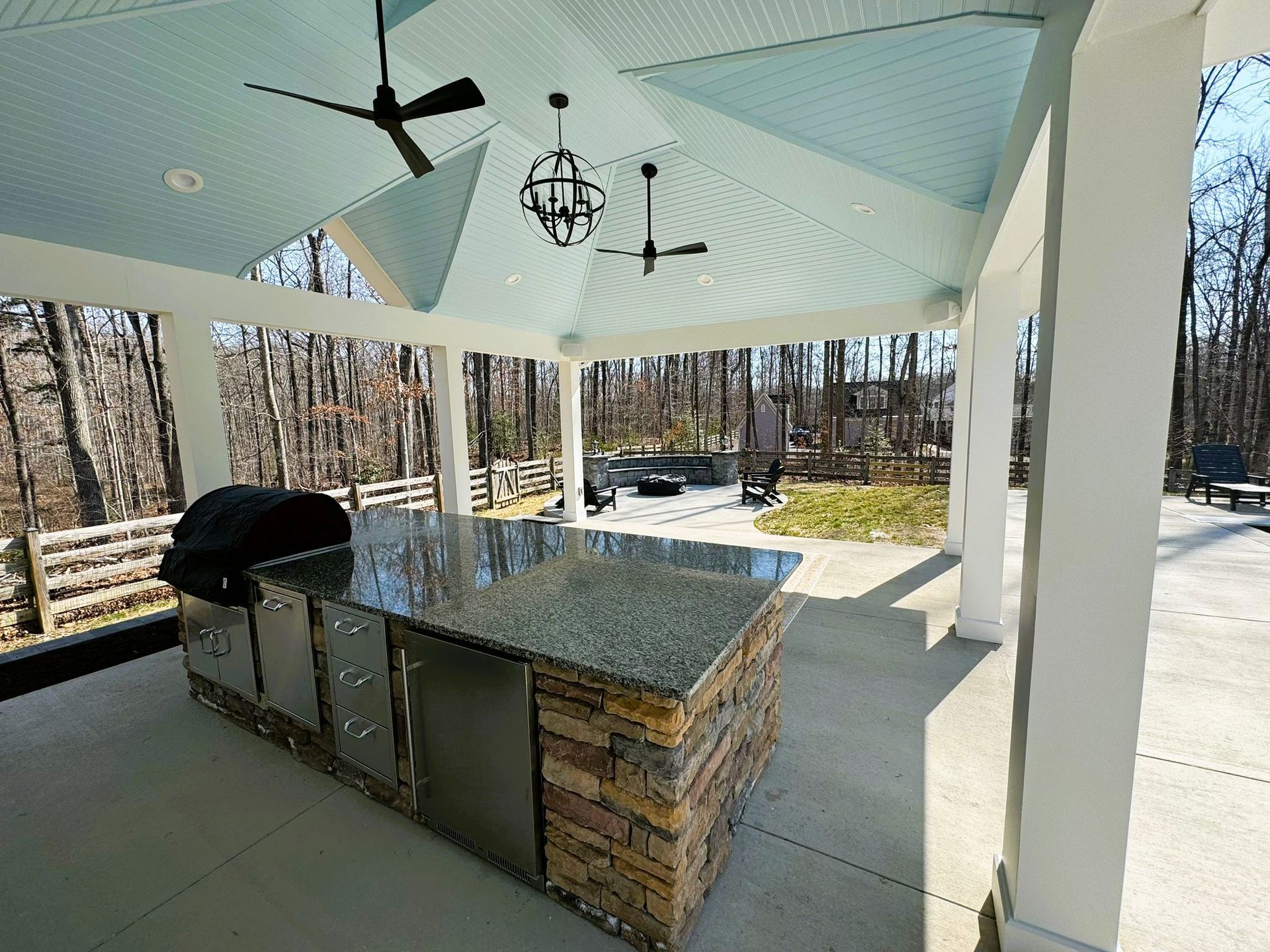 An outdoor kitchen with a grill and a ceiling fan