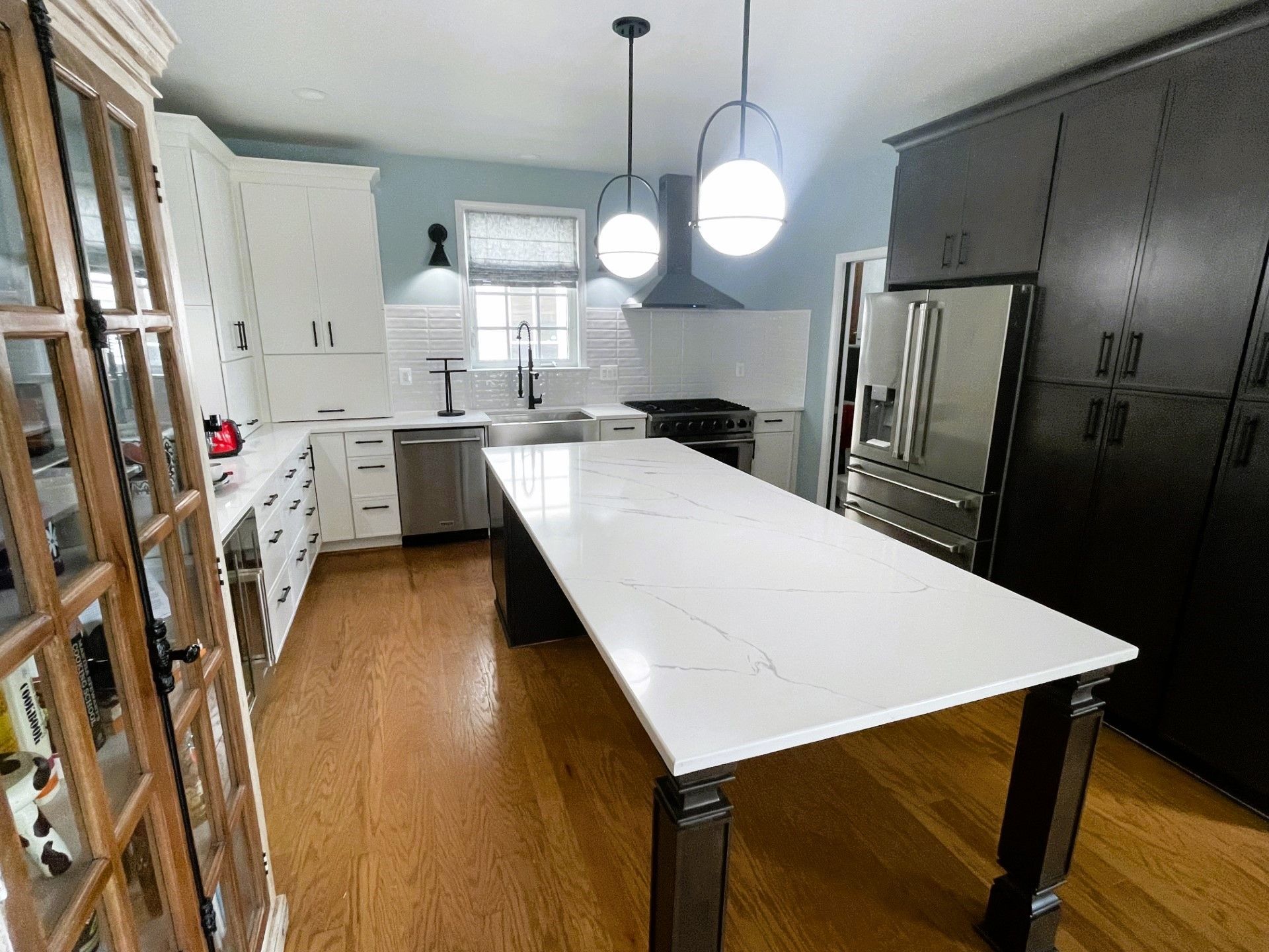 A kitchen with a large white table and stainless steel appliances.