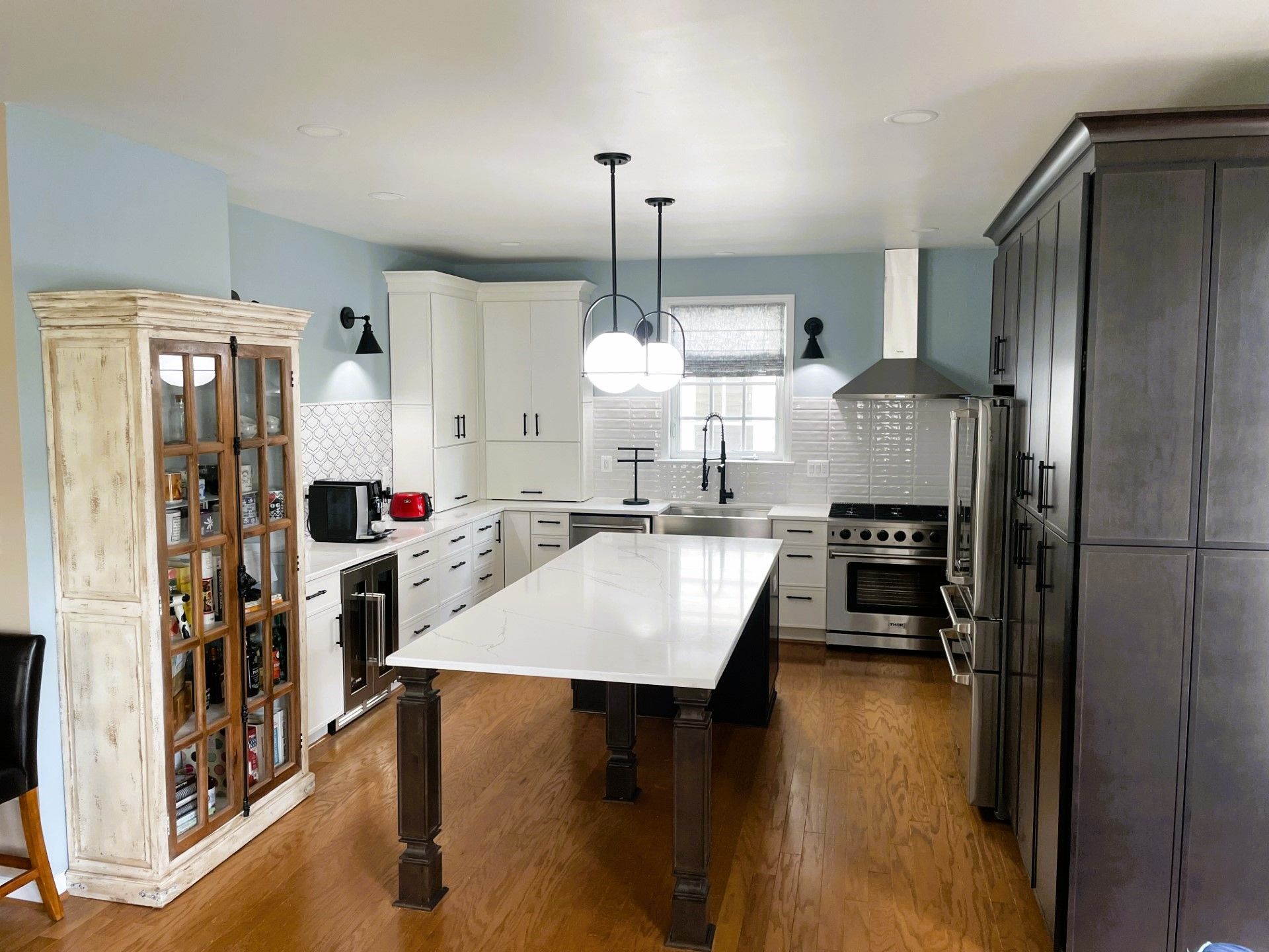 A kitchen with a large island in the middle of it and stainless steel appliances.