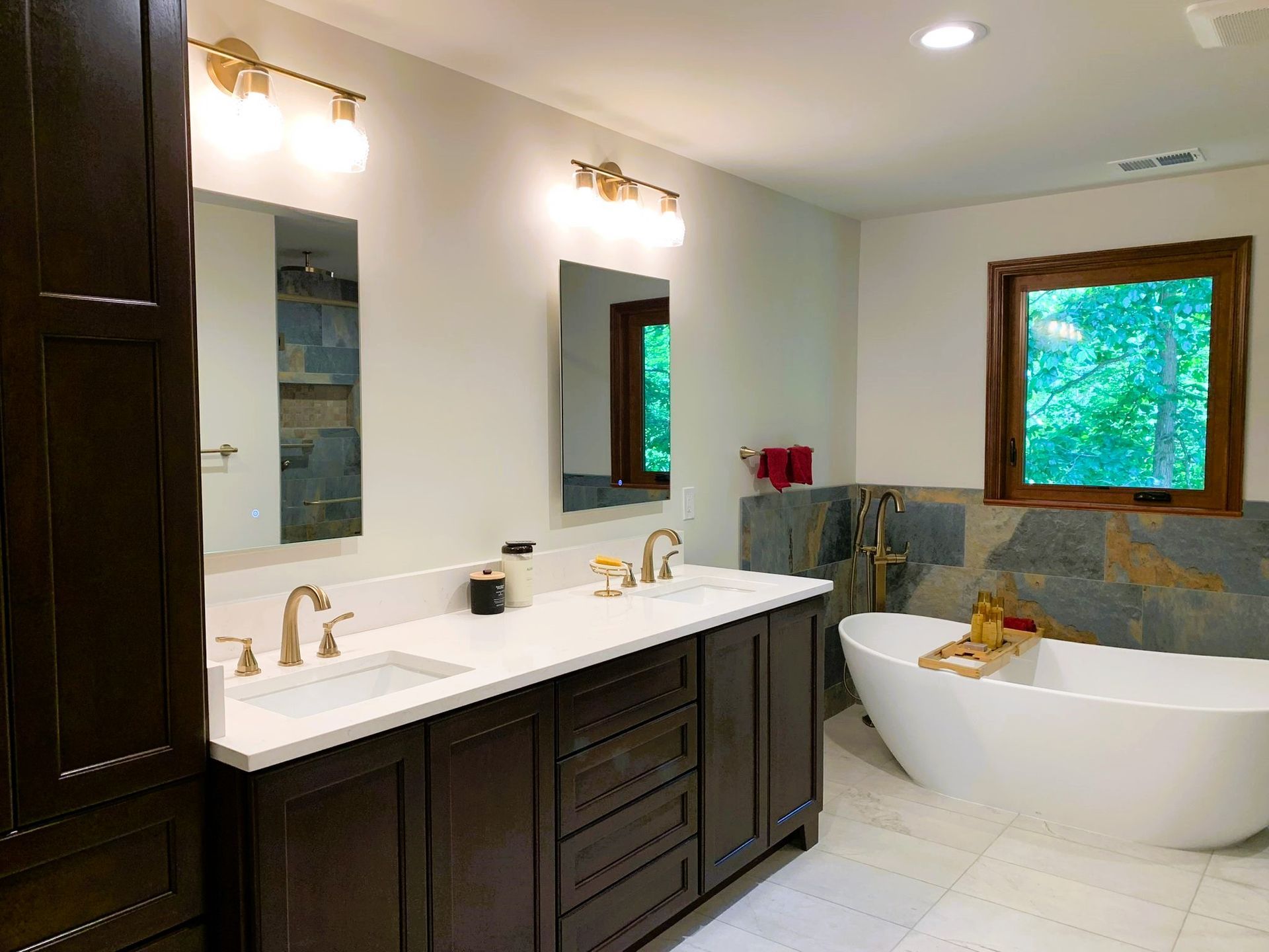 A bathroom with two sinks, a tub, and a window.