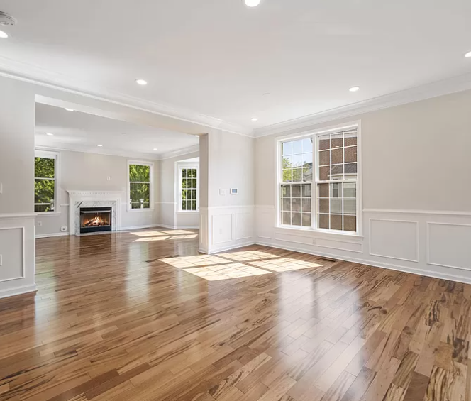 An empty living room with hardwood floors and a fireplace.