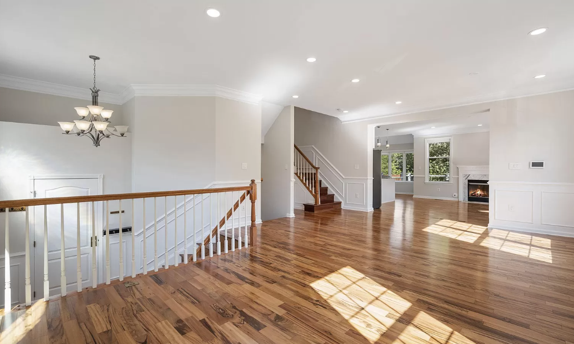 A large empty room with hardwood floors and stairs in a house.
