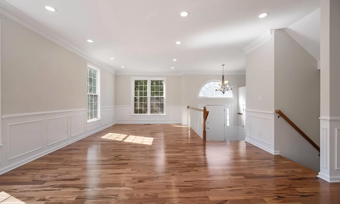 An empty living room with hardwood floors and white walls.