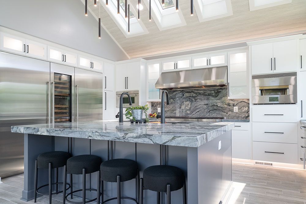 A kitchen with white cabinets, stainless steel appliances, and a large island with stools