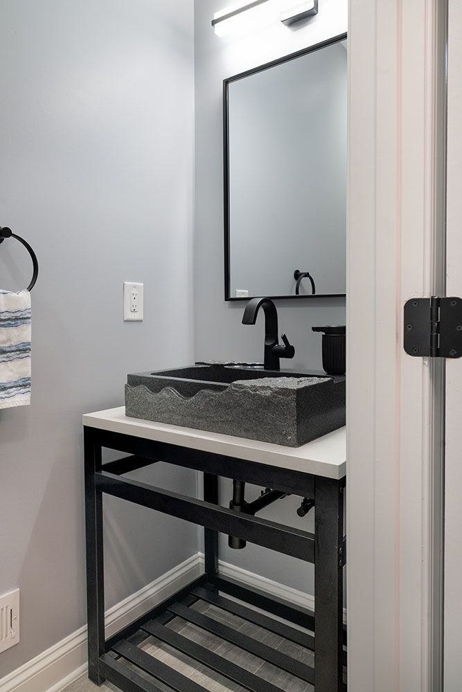 A bathroom with a sink, mirror and towel rack