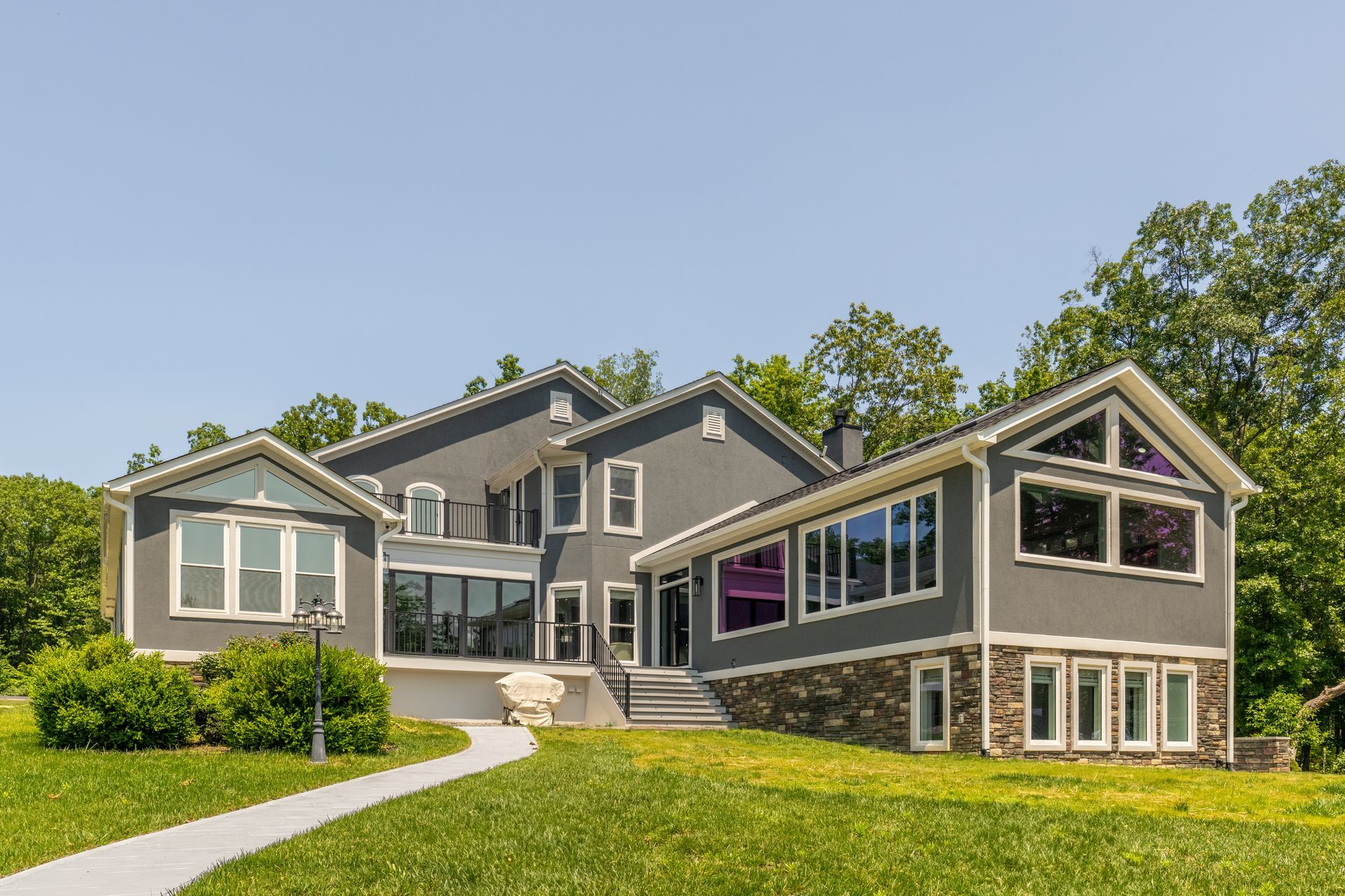 A large house with a lot of windows is sitting on top of a lush green hillside