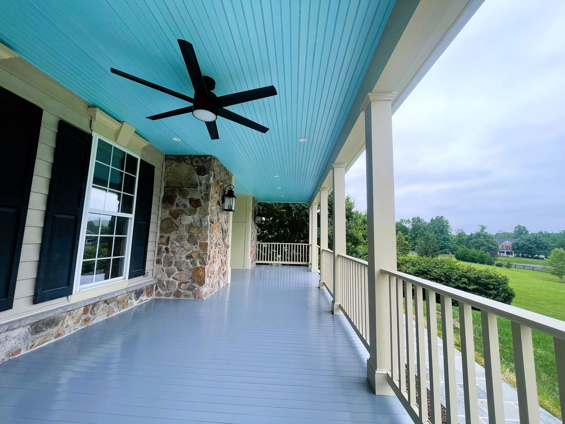A porch with a blue ceiling and a ceiling fan