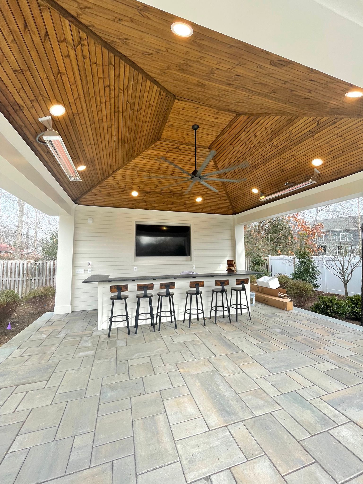 A patio with a wooden ceiling and a ceiling fan.