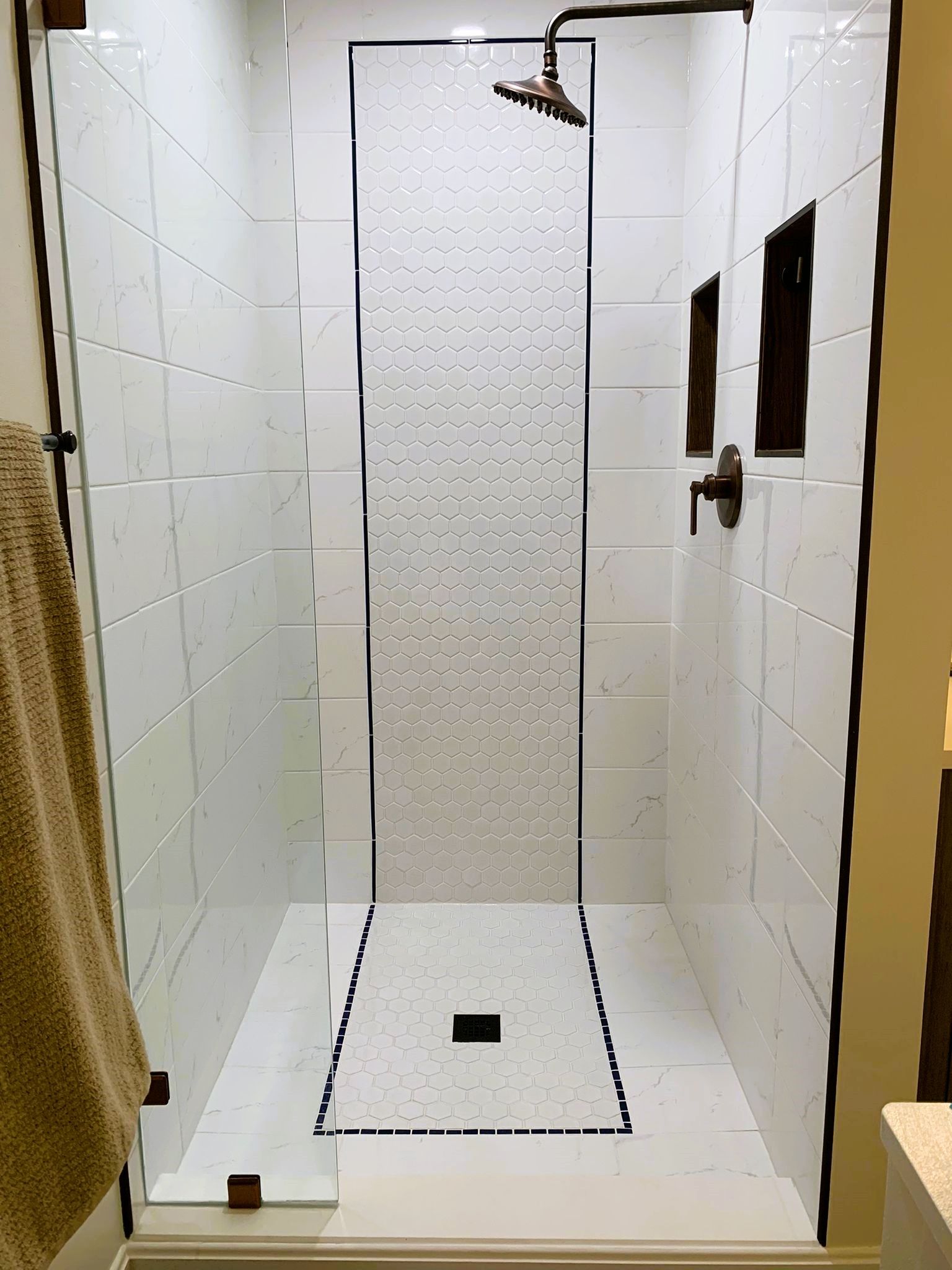 A bathroom with a walk in shower with a glass door and a shower head.