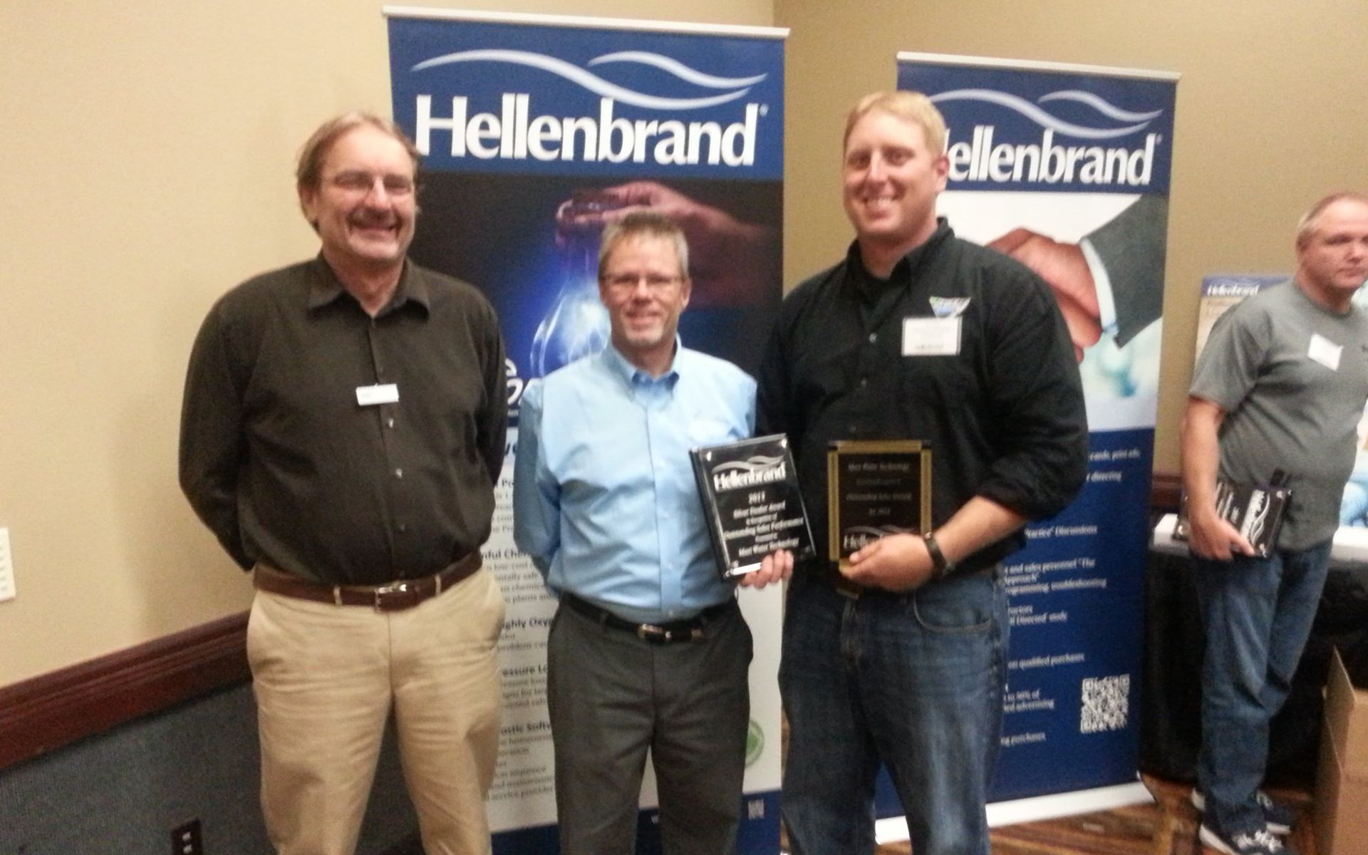 Three men standing in front of a banner that says hellenbrand