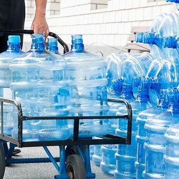 A man is pushing a cart full of water bottles.