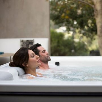 A man and a woman are laying in a hot tub.