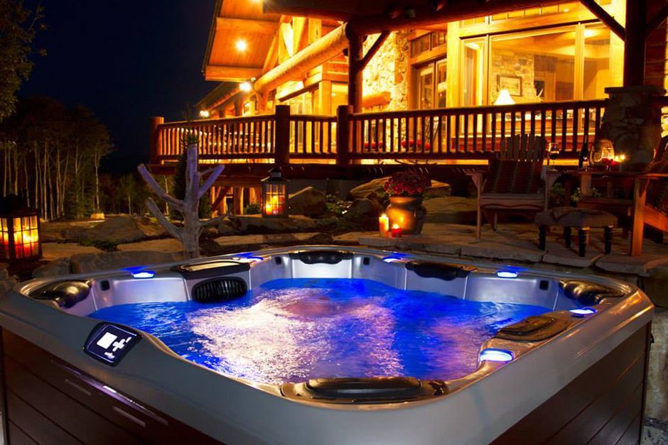 A hot tub is lit up at night in front of a house.