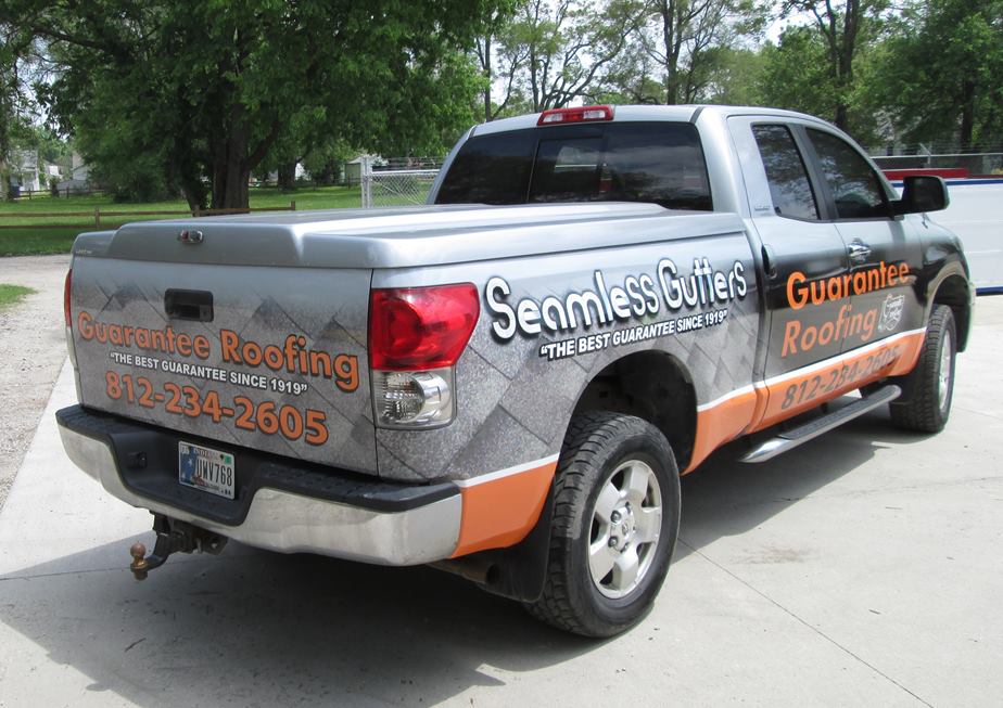 Silver Toyota Tundra pickup truck with Guaranteed Roofing ad wrap.