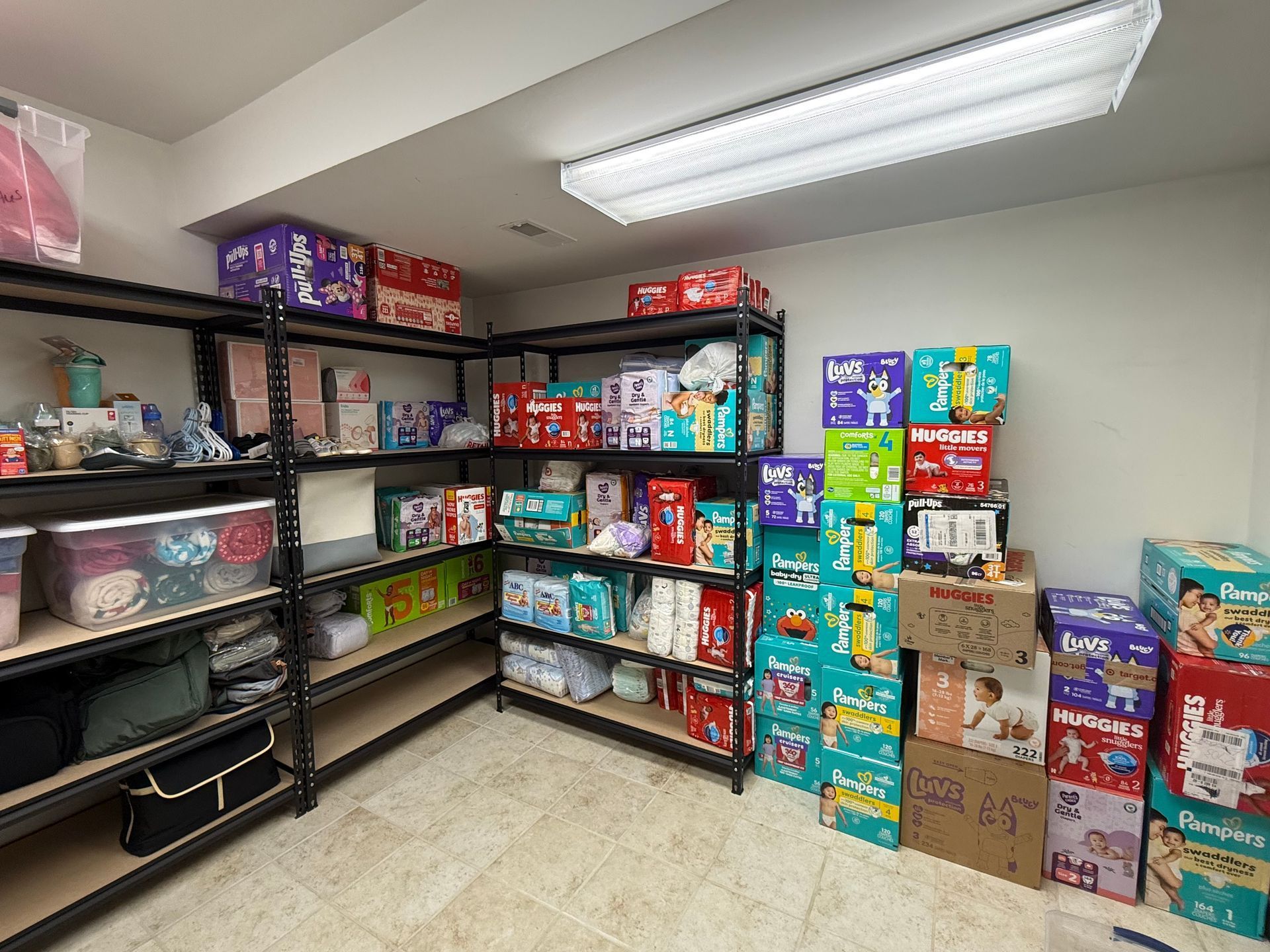 Shelves packed with boxes of diapers and baby supplies in a storage room.