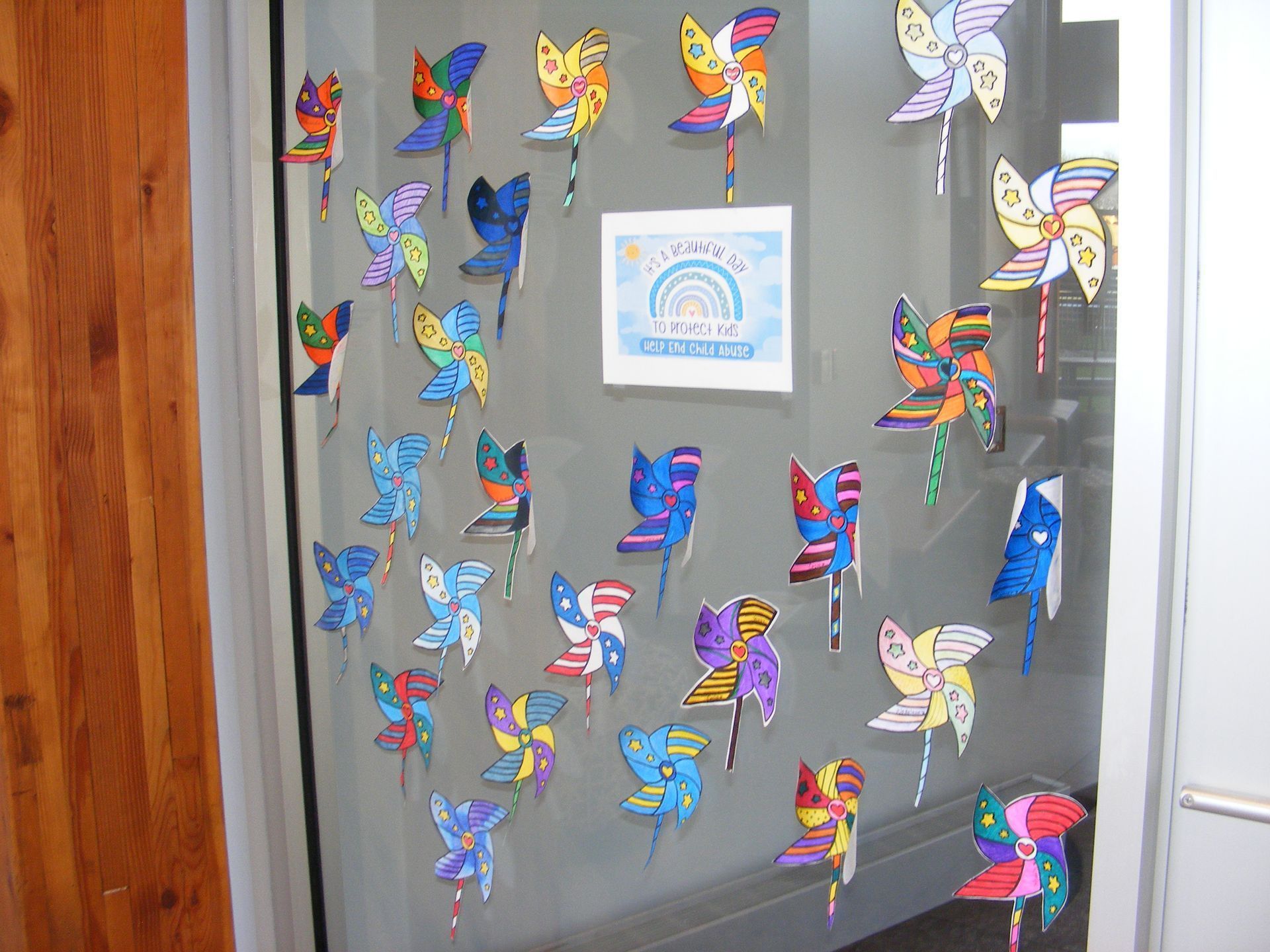 Pinwheels with colorful designs on a window, a card with a rainbow is also displayed
