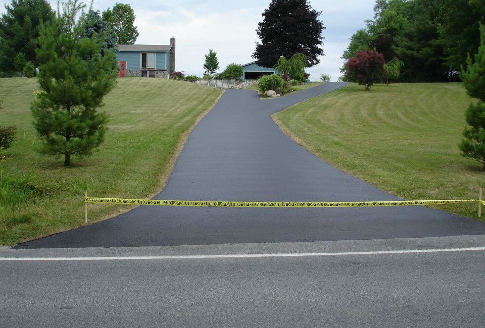 A driveway leading to a house with grass on both sides