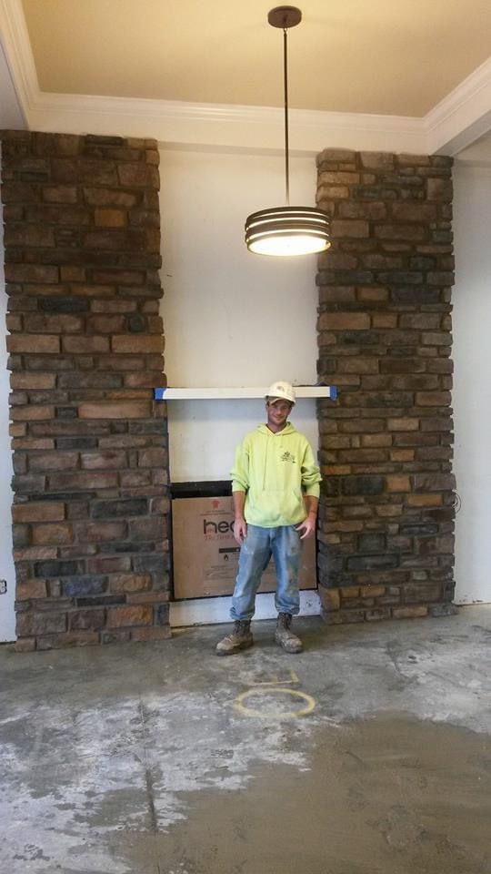 A man is standing in front of a fireplace in a room.