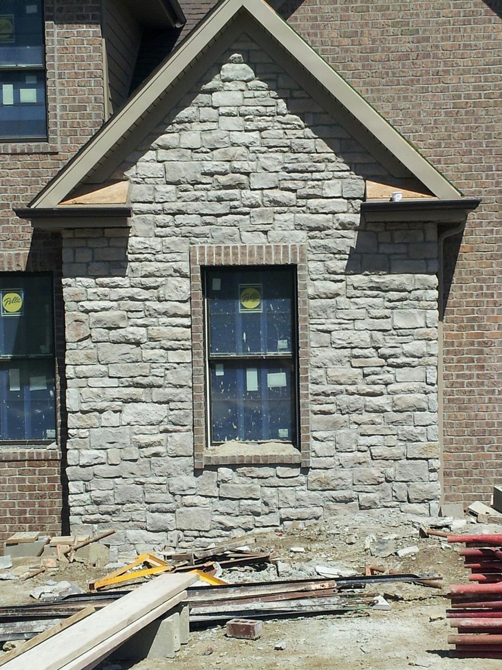 A brick house is being built with a stone facade
