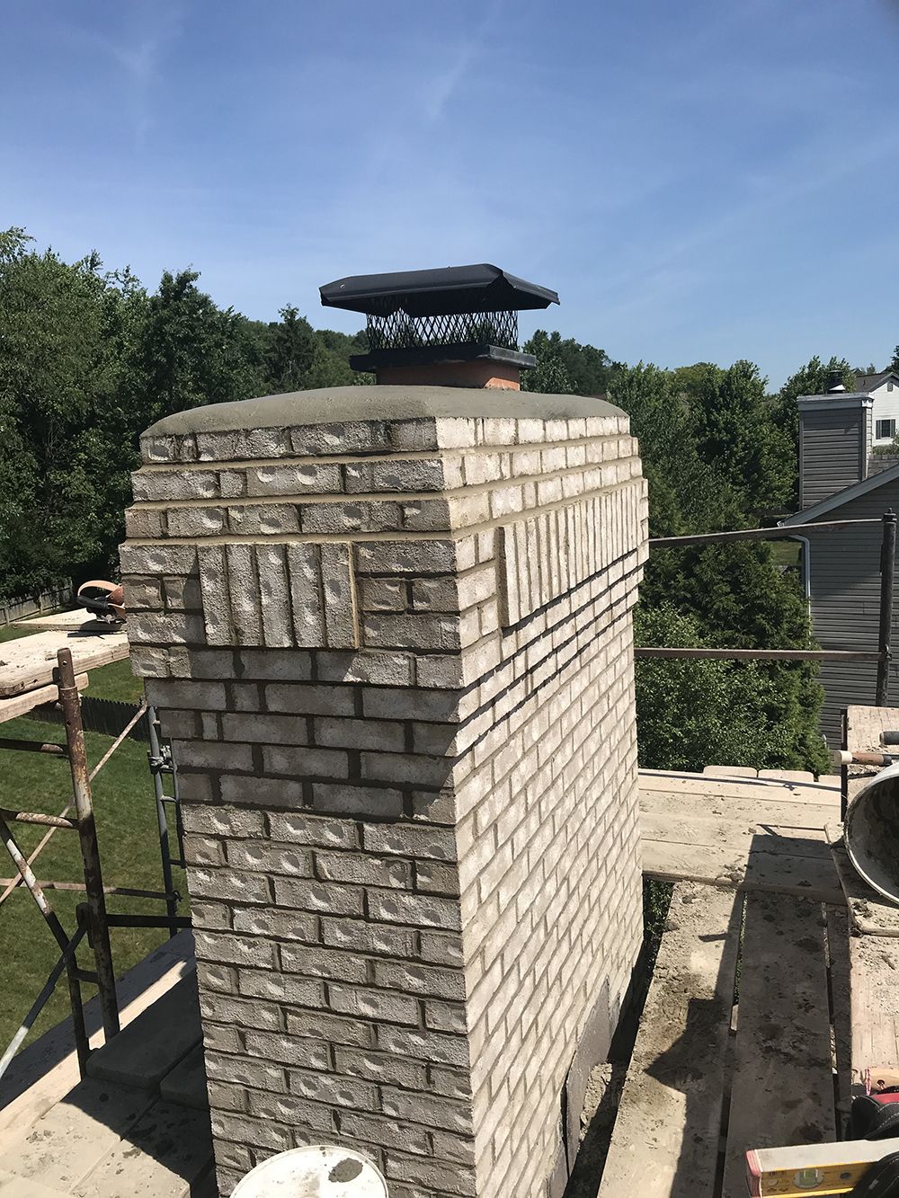 A brick chimney is being built on top of a roof.