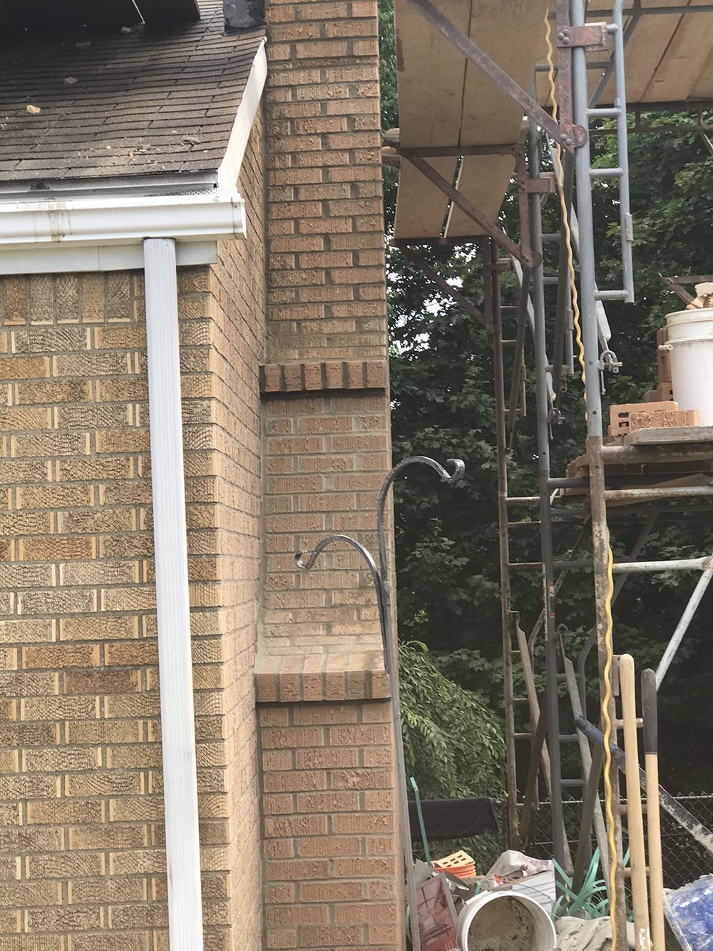 A brick chimney is being built on the side of a house