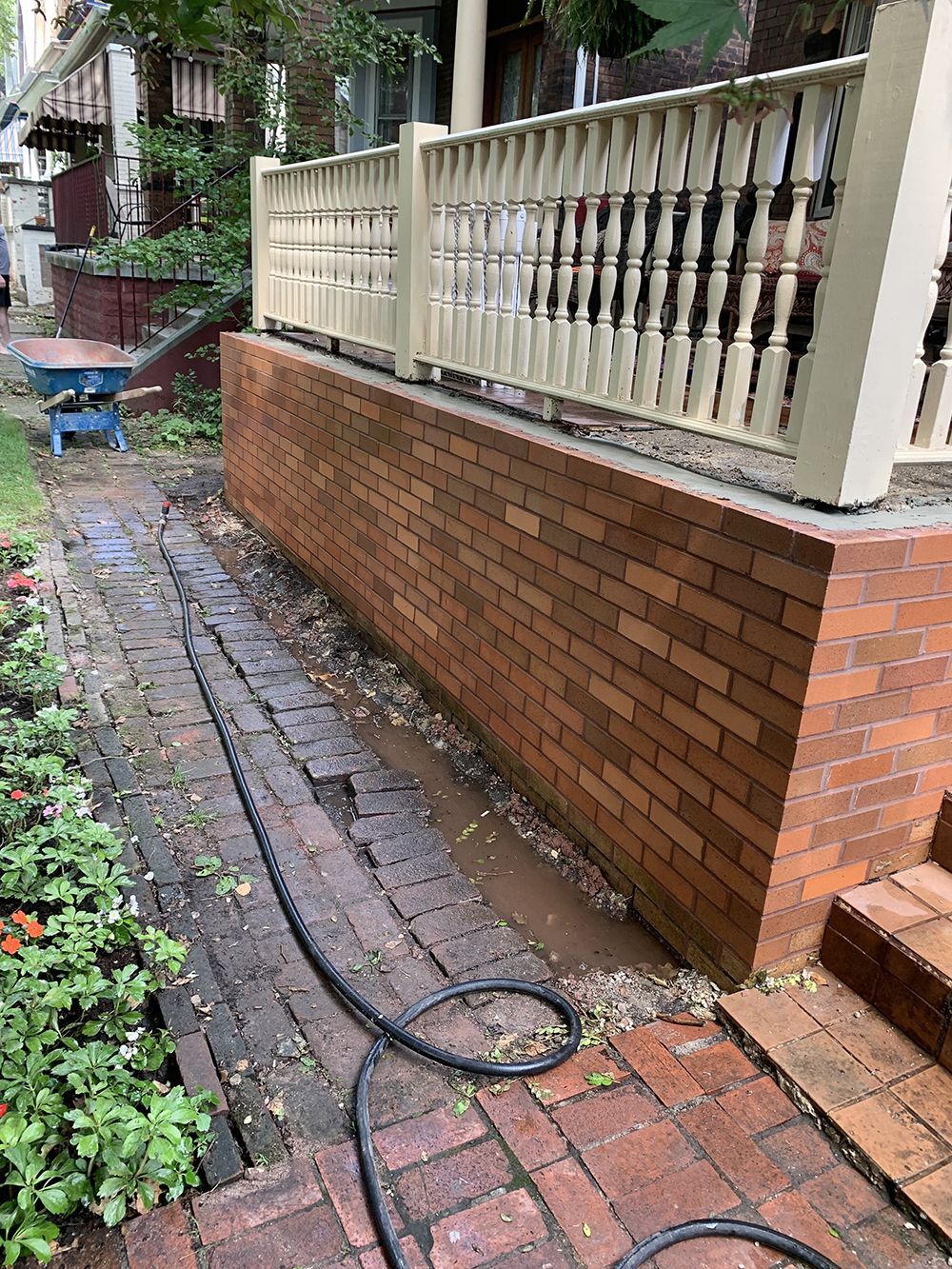 A hose is connected to a brick wall next to a porch.