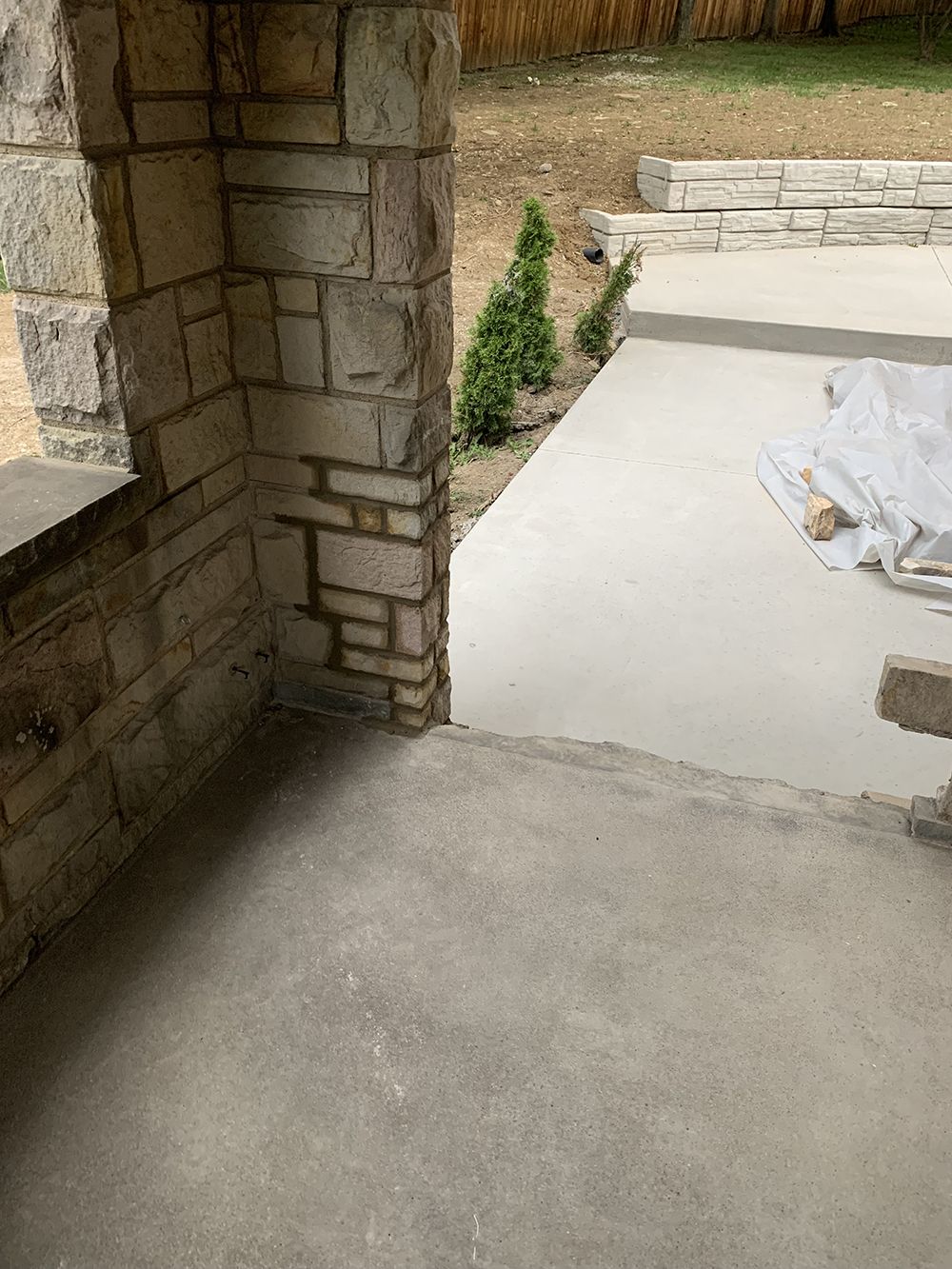 A concrete patio with a stone wall and a bench.