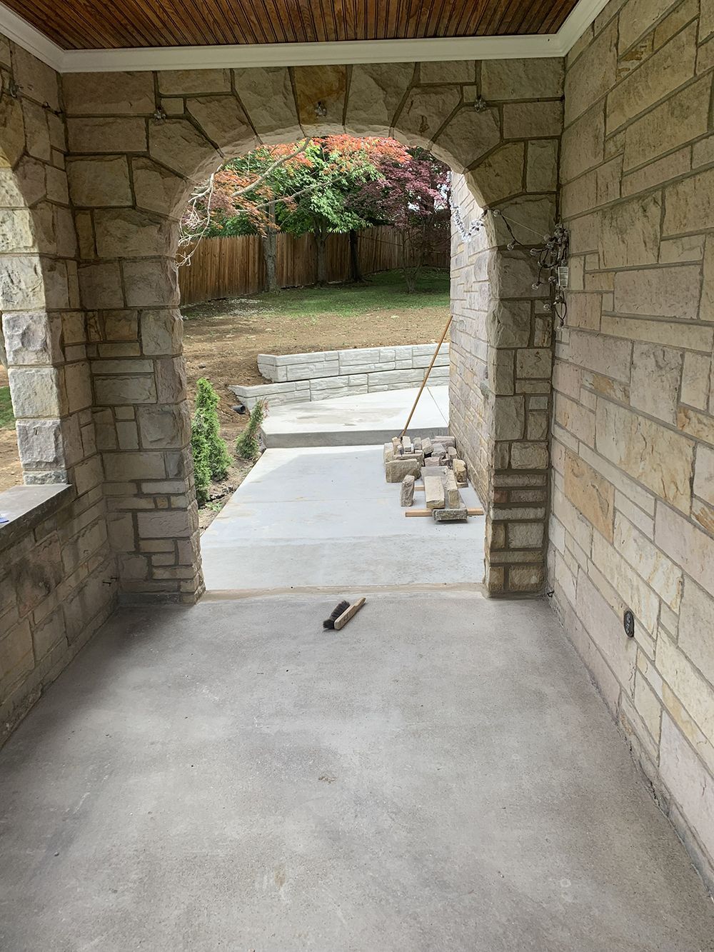 A stone porch with a concrete walkway leading to a backyard.