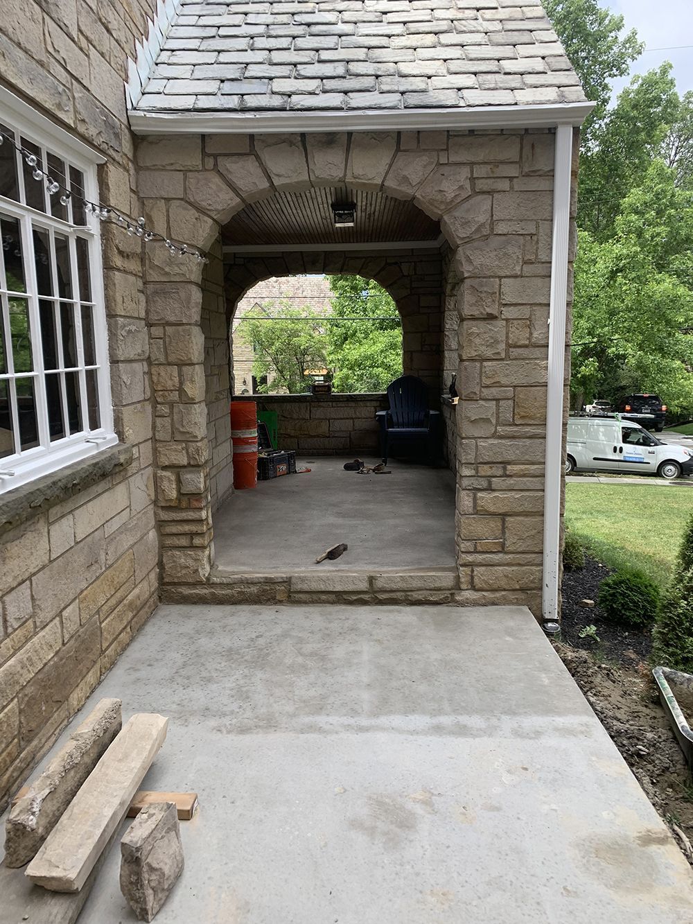 A stone building with a concrete walkway leading to a garage.