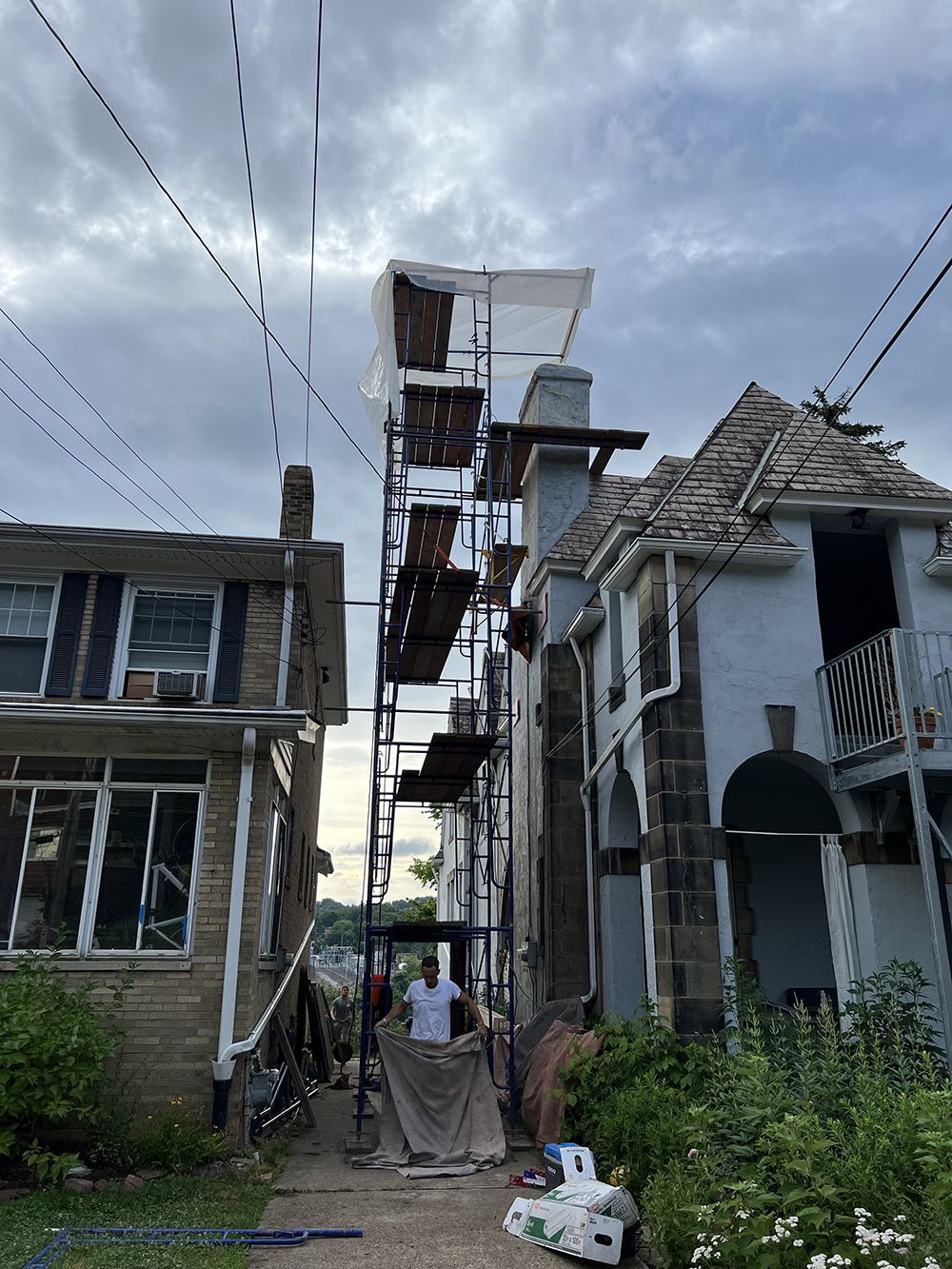 A man is standing on a scaffolding next to a house.