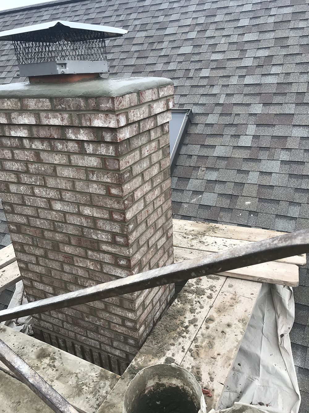 A brick chimney is sitting on top of a roof.