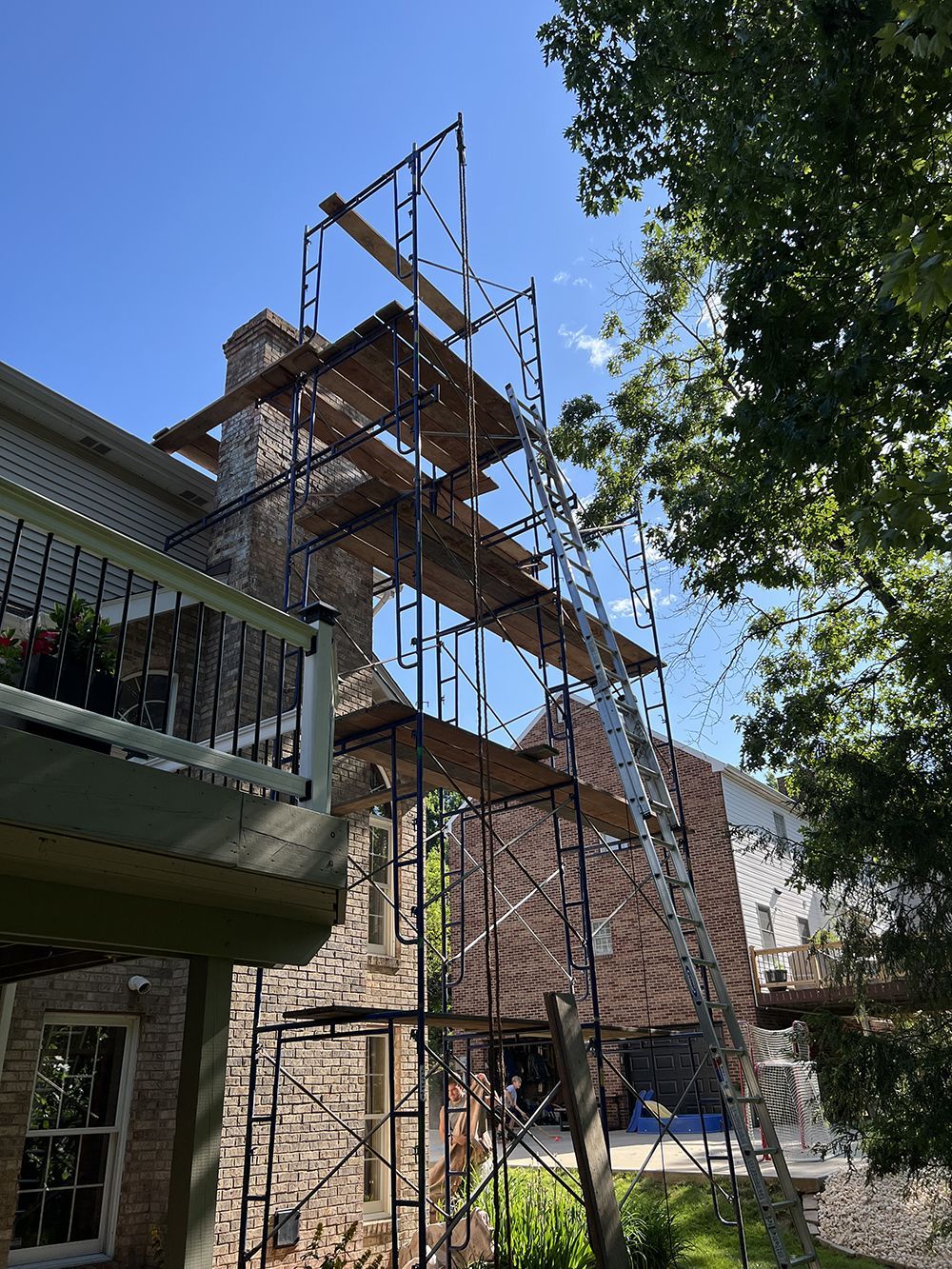 A scaffolding is being used to repair a chimney on the side of a house.