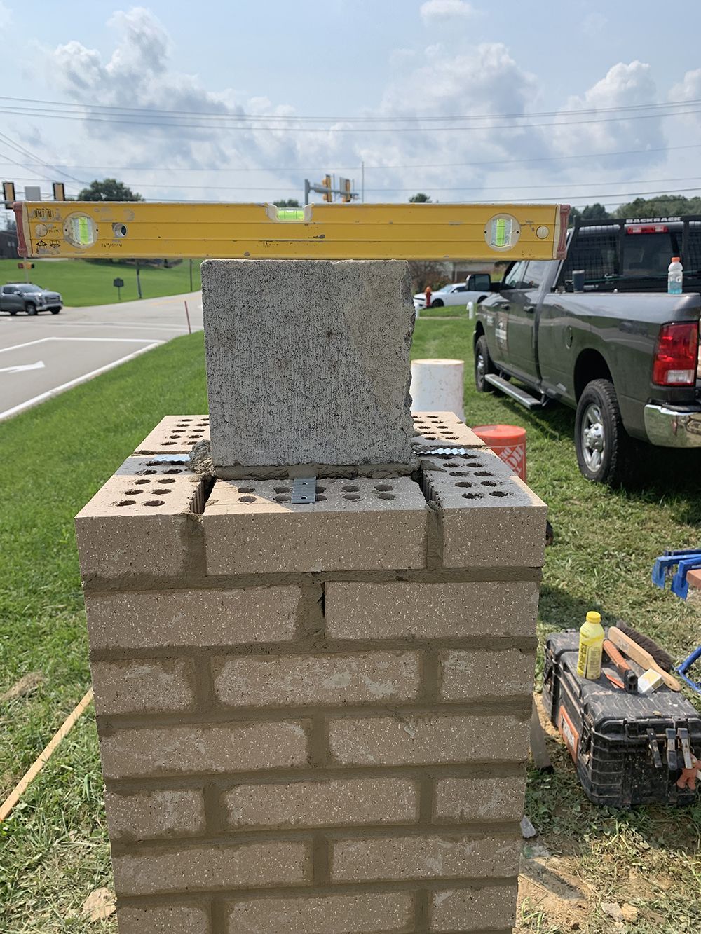 A brick pillar is being built next to a truck.