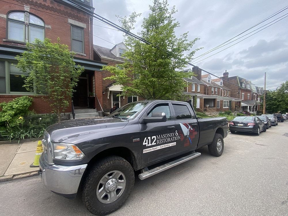 A black truck is parked on the side of the road in front of a brick building.