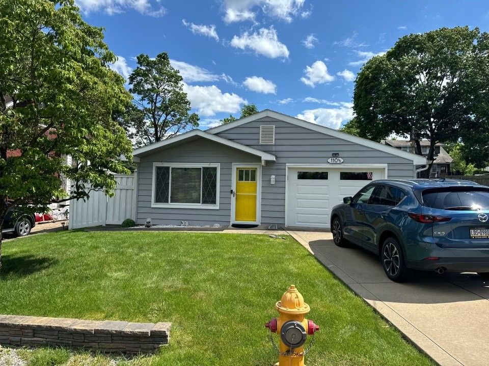 A blue car is parked in front of a house with a yellow door.