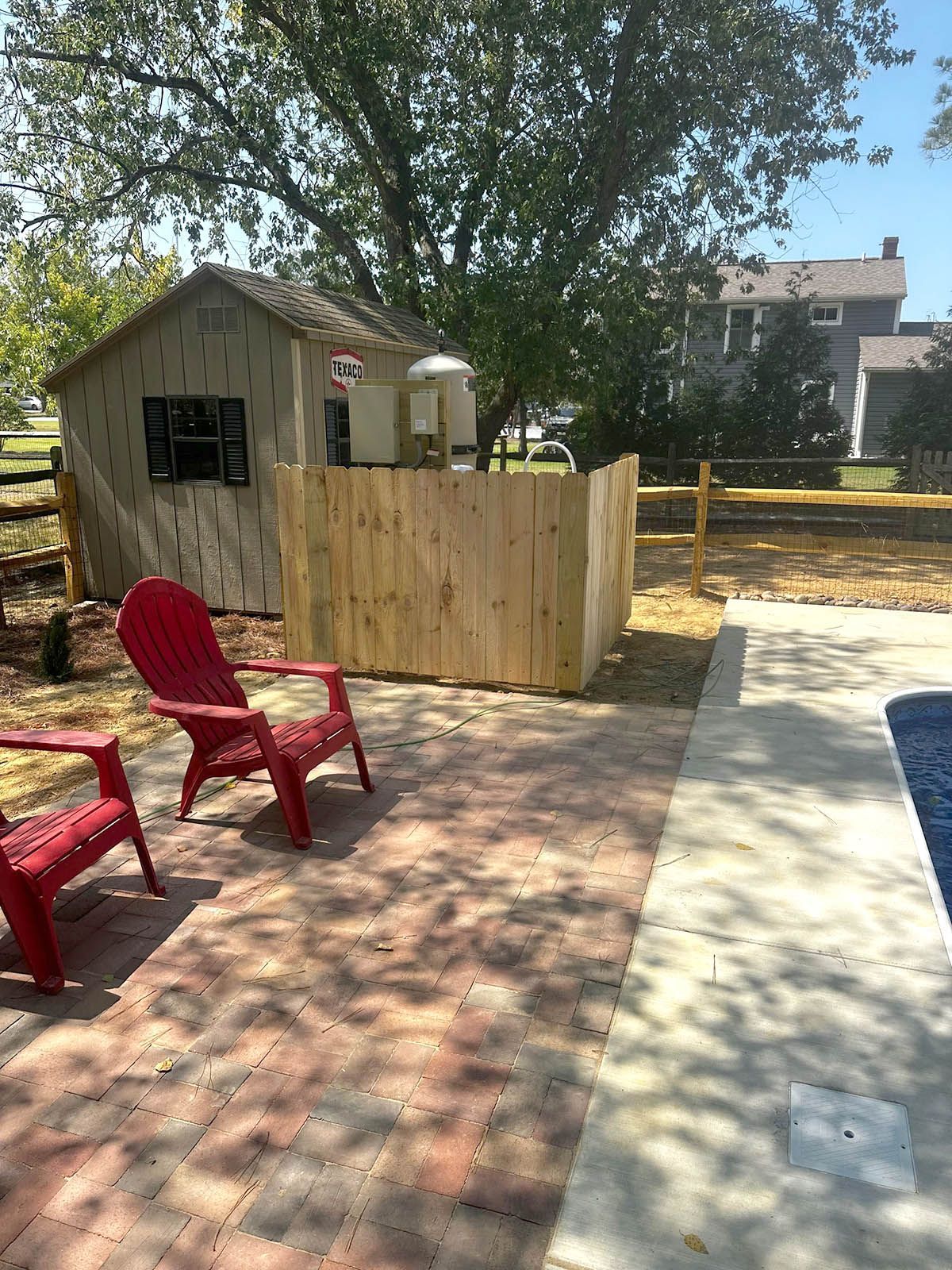 A newly installed wooden fence beside the two red chairs
