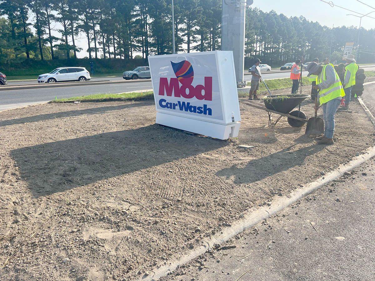 A car wash sign is sitting on the side of the road