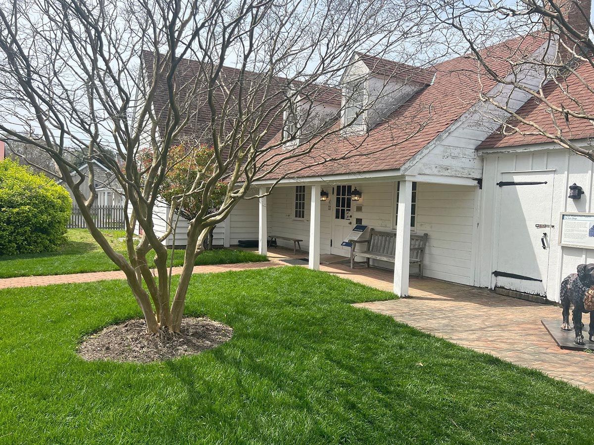 A white house with a porch and a horse statue in front of it