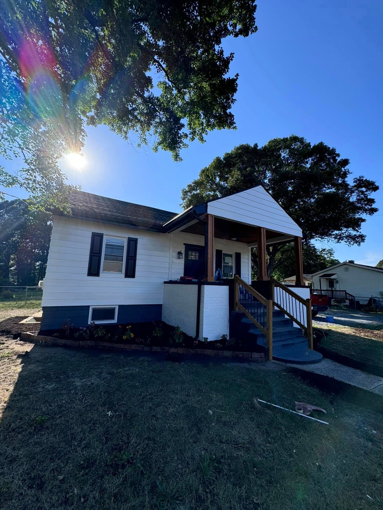 A small white house with a porch and stairs