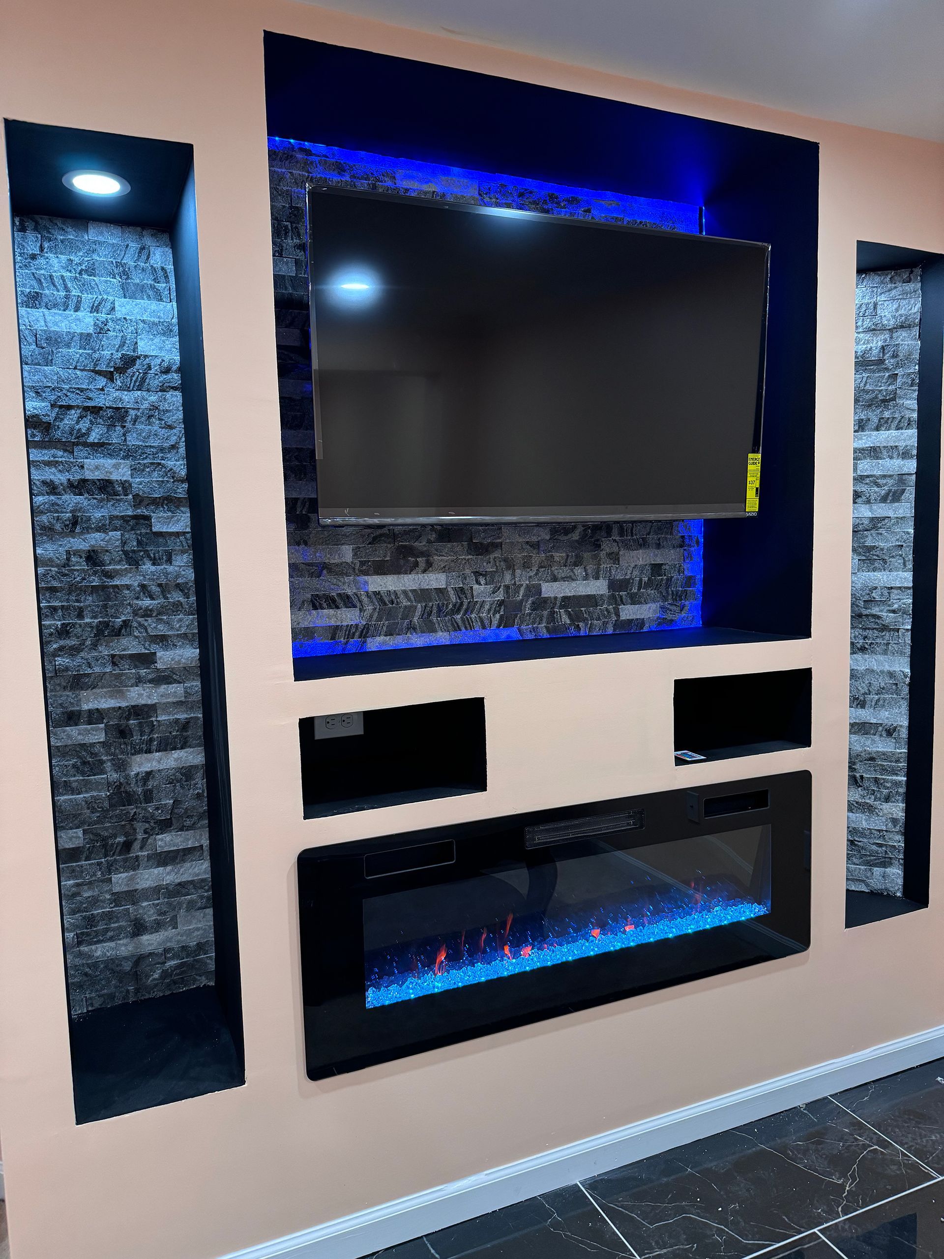 A living room with a fireplace and a flat screen tv on the wall.