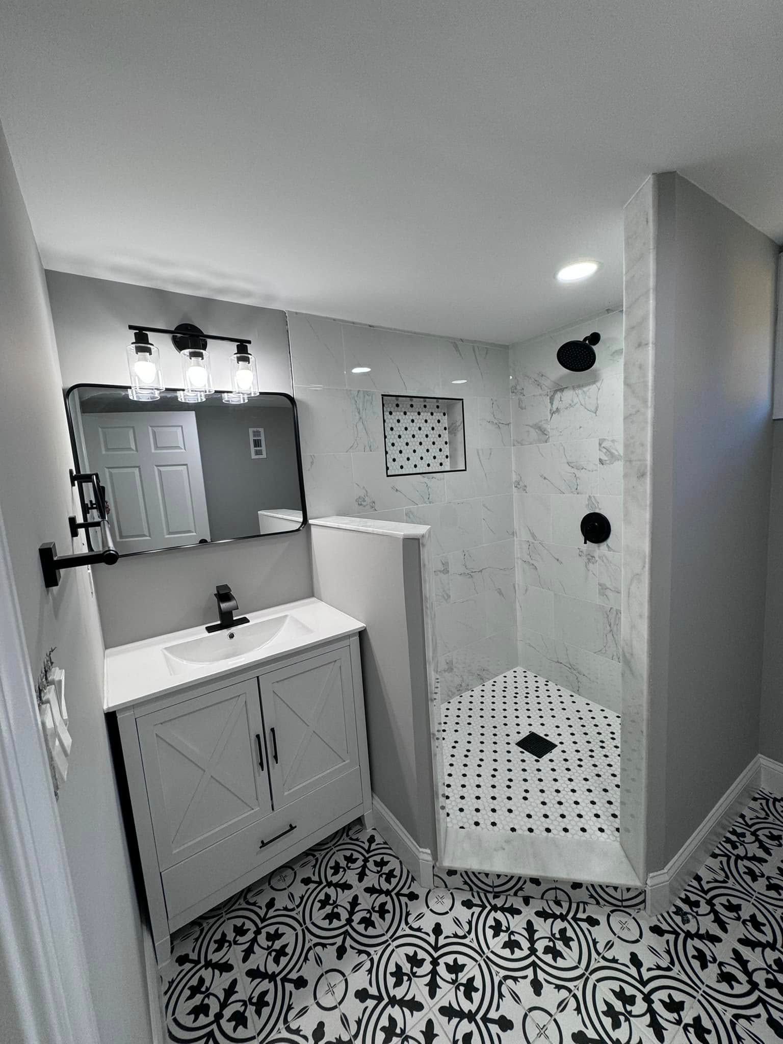 A bathroom with a sink , mirror , and walk in shower.