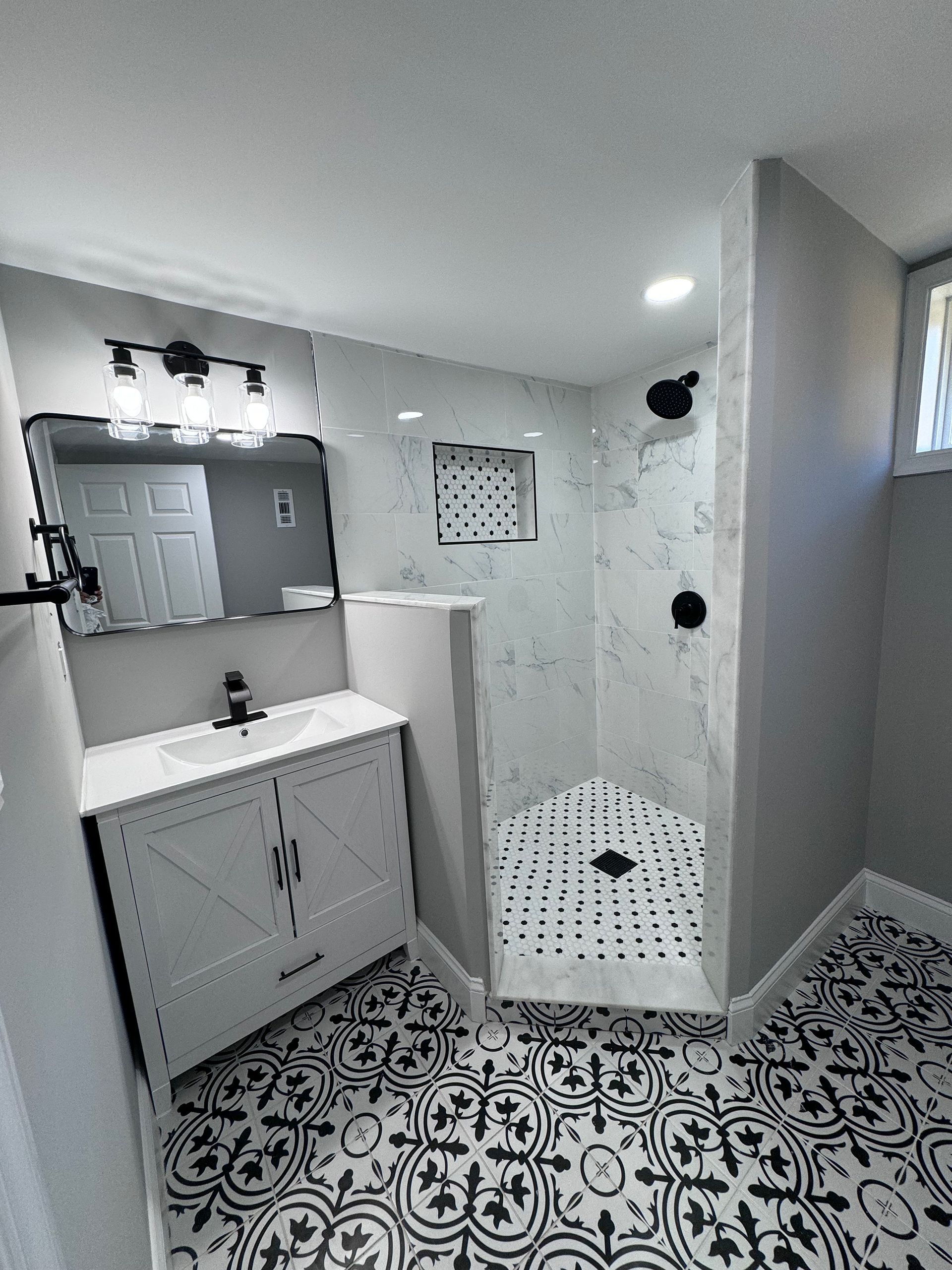 A bathroom with a walk in shower, sink and mirror.
