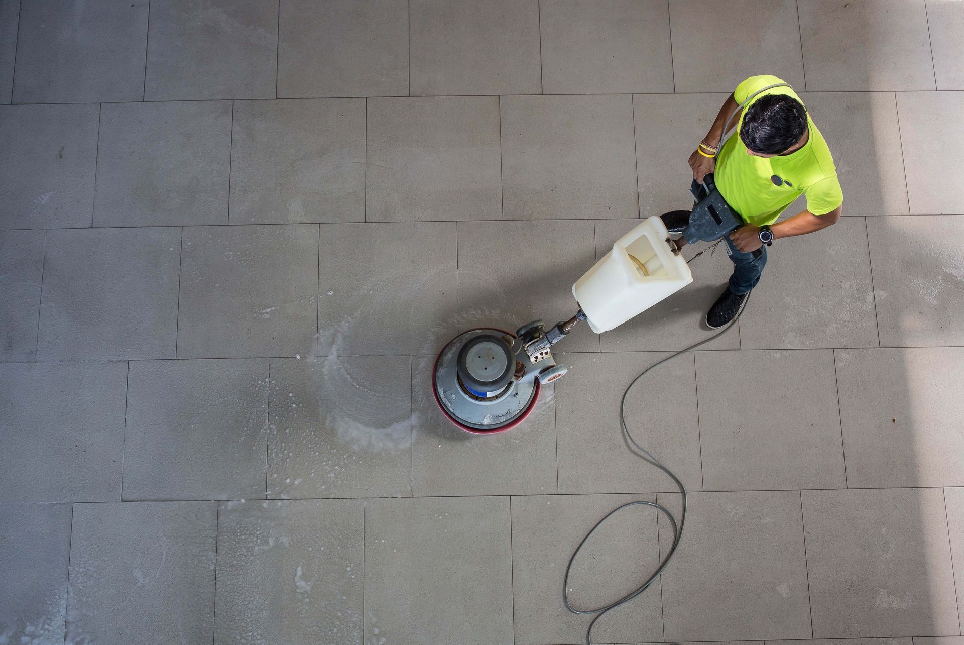 A man is cleaning a tiled floor with a machine