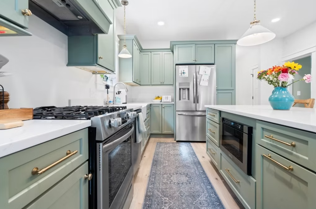 A kitchen with green cabinets and stainless steel appliances.