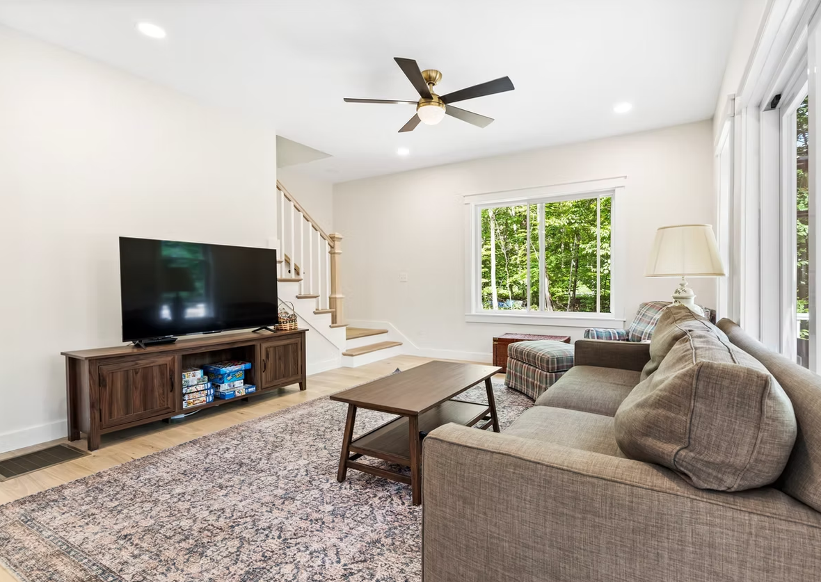 A living room with a couch, television, and ceiling fan.