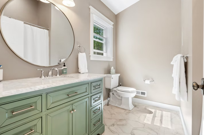A bathroom with a sink, toilet, and mirror.