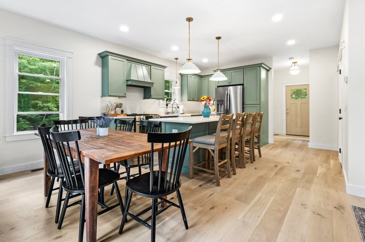 A kitchen with a wooden table and chairs and a large island.